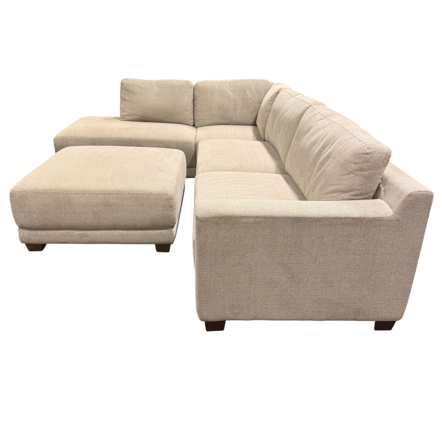 Couch Quest modular sectional sofa in light beige fabric with a matching ottoman and dark low-profile feet.