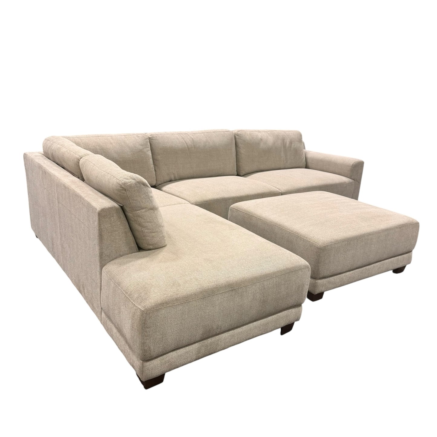 Couch Quest modular sectional sofa in light beige fabric with a matching ottoman and dark low-profile feet.