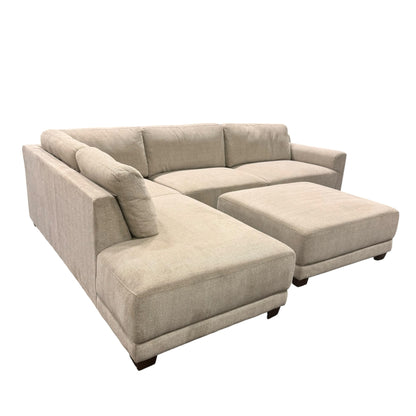 Couch Quest modular sectional sofa in light beige fabric with a matching ottoman and dark low-profile feet.